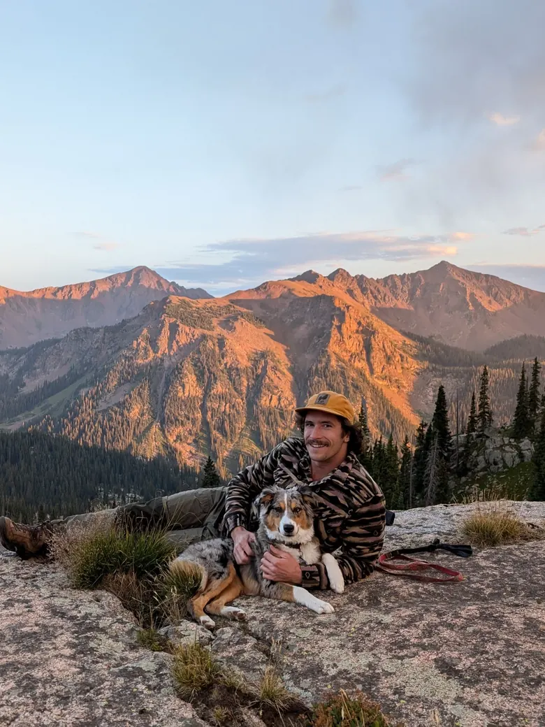 Mark Placek and his dog on a granite ledge above a Colorado valley at sunset